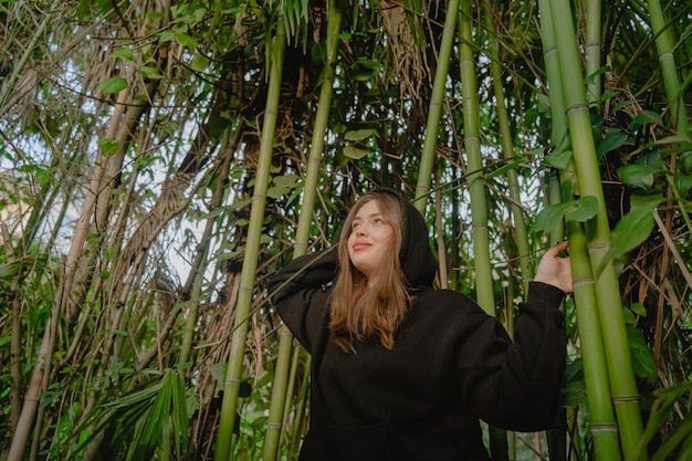 Chica mirando hacia arriba en un bosque de bambú