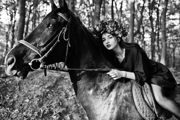 Chica mística en ropa de corona en negro a caballo en madera