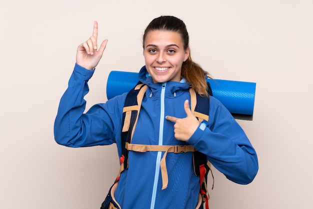 Chica con mochila de alpinista sobre pared aislada