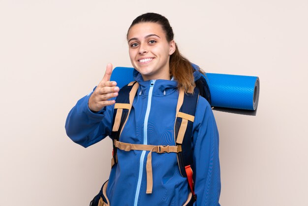 Chica con mochila de alpinista sobre pared aislada