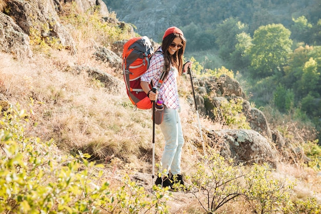 Chica con mochila y bastón de esquí cerca de la imagen de longitud completa del cañón