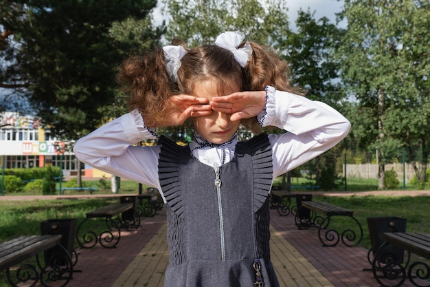 Chica con una mochila cerca de la escuela después de clases infeliz cansada y dolor de cabeza El niño llora sosteniendo su cabeza entre sus manos Fallos académicos malas calificaciones exceso de trabajo