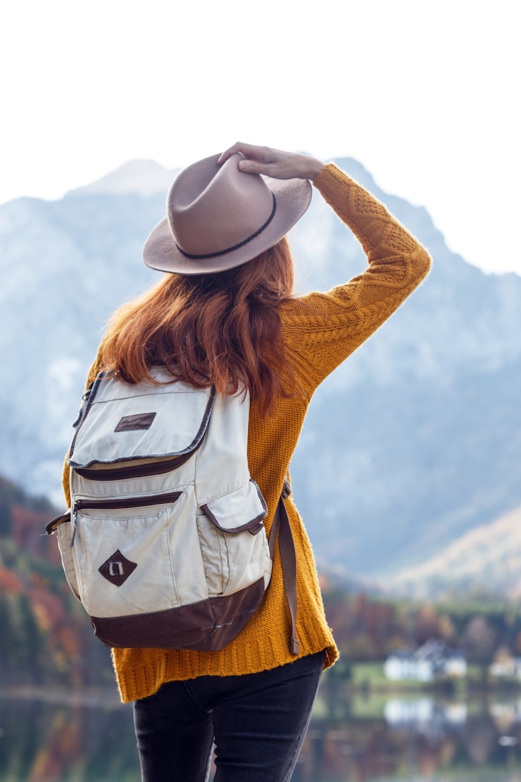 Foto chica con una mochila se encuentra en la orilla de un lago de montaña