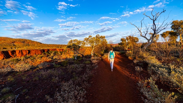 Chica mochilera haciendo senderismo en el parque nacional karijini, australia al amanecer amanecer en el desierto rojo