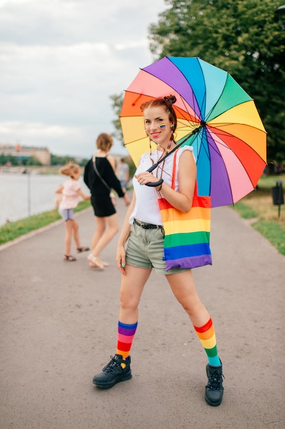 Chica de moda con bandera LGBT en su rostro posando en la calle