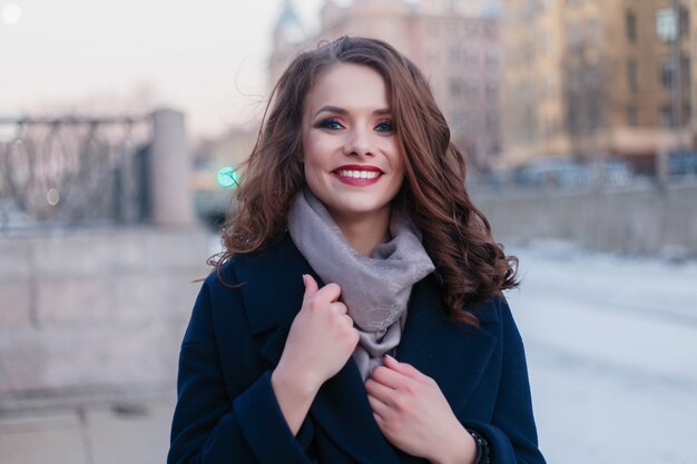 Chica de moda con cabello ondulado posando en la ciudad