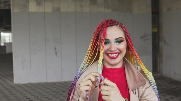 Chica de moda en una chaqueta endereza sus trenzas africanas de colores