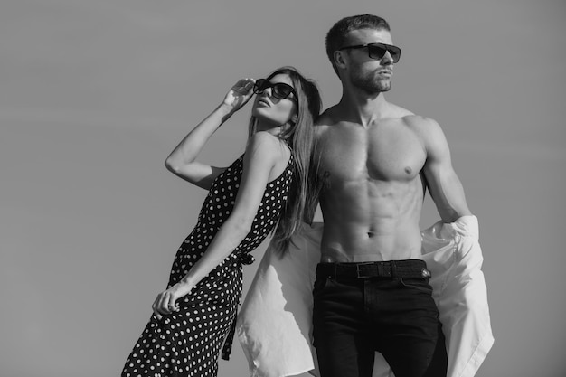 Chica de moda y chico en ropa de salida posando sobre un fondo de cielo azul amantes y día de san valentín