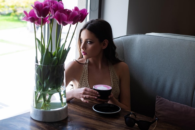 Chica de moda disfrutando de un café en la cafetería. capuchino americano latte espresso.