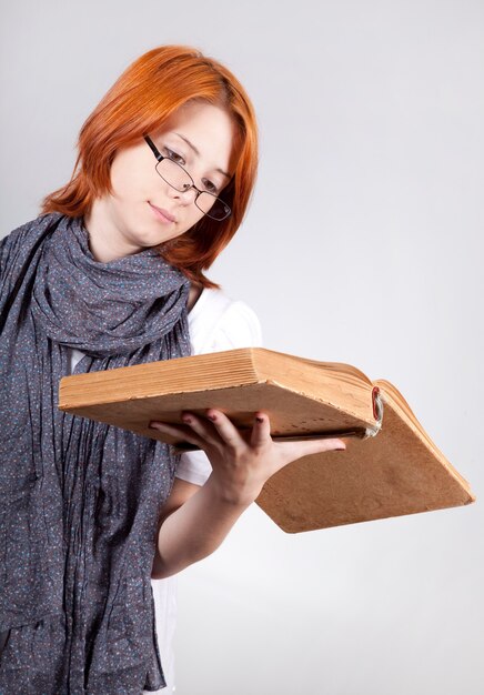 Chica de moda joven dudando en vasos con libro antiguo