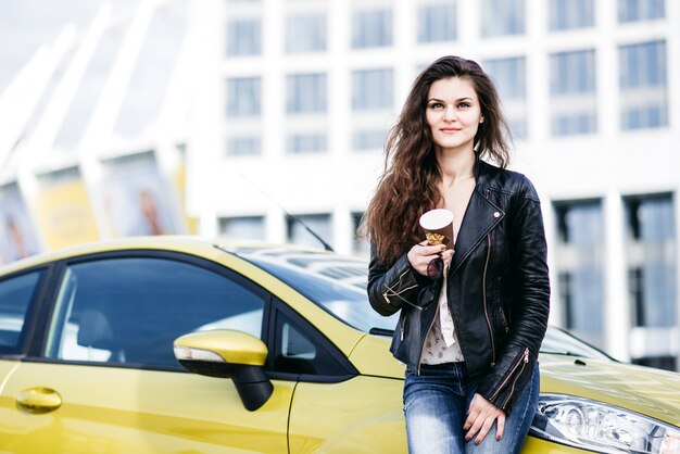 Foto chica de moda junto a su coche en la ciudad moderna