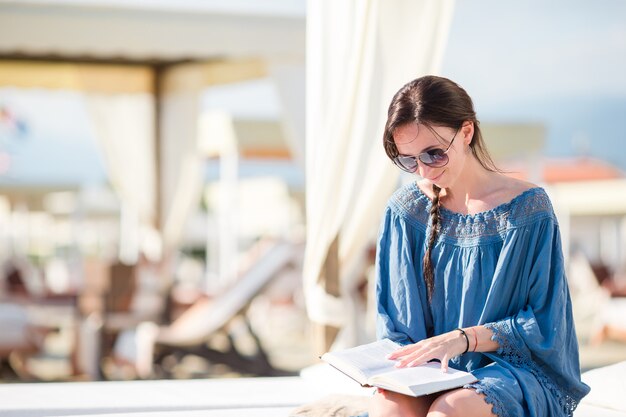 Chica de moda leer sentado en hamacas blancas en el europeo beach weekeend