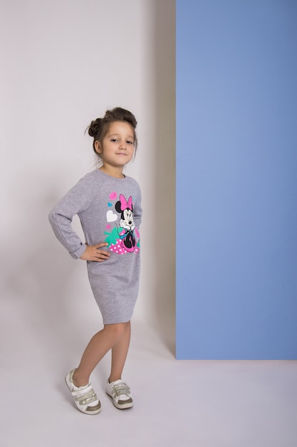 Chica de moda en ropa elegante sobre fondo de pared color. Otoño ropa brillante en niños, un niño posando