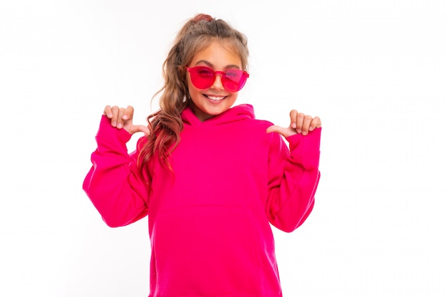 Chica de moda en sudadera rosa, gafas de sol rosadas es feliz y sonrisas aislado sobre fondo blanco.