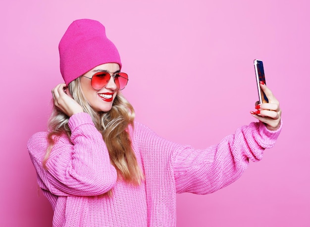 Chica de moda tomando foto hace autorretrato en smartphone wea