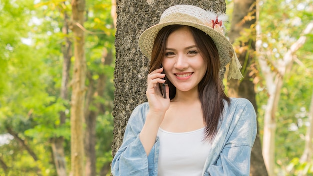 Chica de moda usar teléfono en el parque jardín.