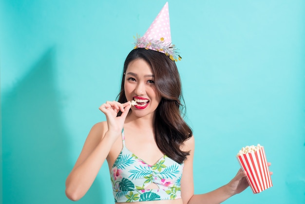 Chica de moda de verano en traje de verano comiendo palomitas de maíz.