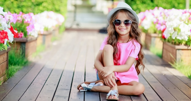 Chica de moda vistiendo una camisa a cuadros rosa, sombrero y gafas de sol en la ciudad