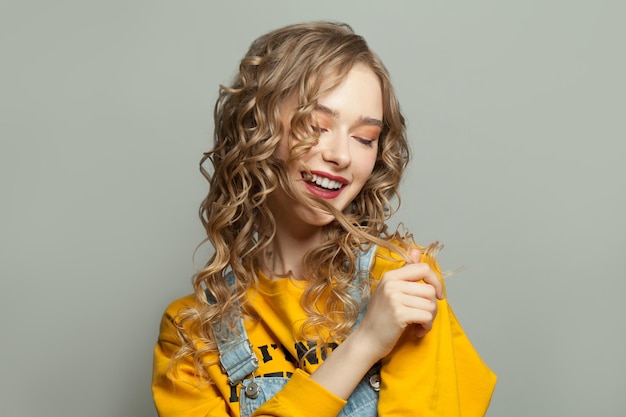 Chica modelo alegre sonriendo sobre un fondo gris