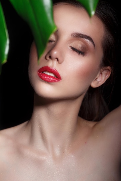 Chica modelo de belleza con maquillaje perfecto y labios rojos sobre fondo negro