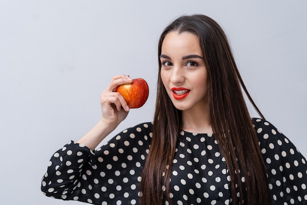 Chica modelo de belleza posando con manzana sobre fondo blanco. Chica guapa mira a la cámara.