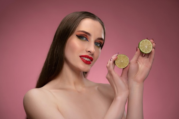 Chica modelo de belleza sosteniendo dos jugosas rodajas de limón por la mitad en sus manos mirando hacia los lados encantador joyfu ...