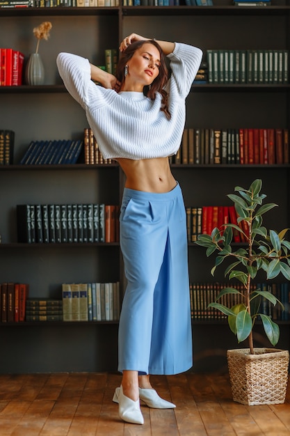 Chica modelo en una blusa blanca y pantalón azul, con el telón de fondo de las estanterías