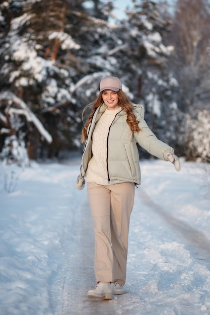 Una chica modelo caminando por un bosque cubierto de nieve una demostración de ropa