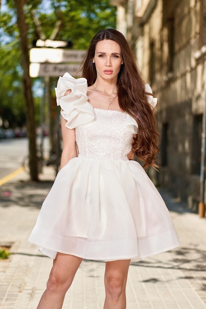 Chica modelo con un vestido blanco en la calle.