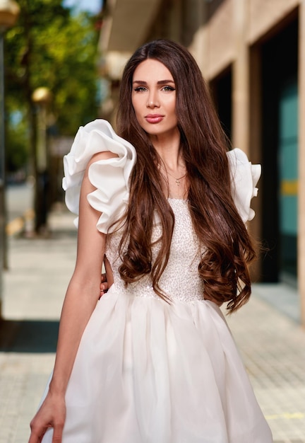 Chica modelo con un vestido blanco en la calle.