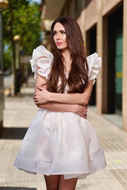 Chica modelo con un vestido blanco en la calle.