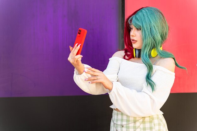 Una chica moderna con el cabello rojo y verde tomando una foto con su teléfono