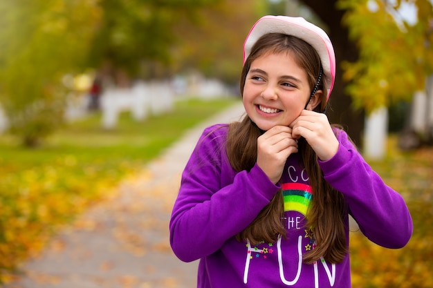 Chica con un moderno casco rosa con una sonrisa feliz en un parque de otoño. Concepto de vacaciones y pasar tiempo.