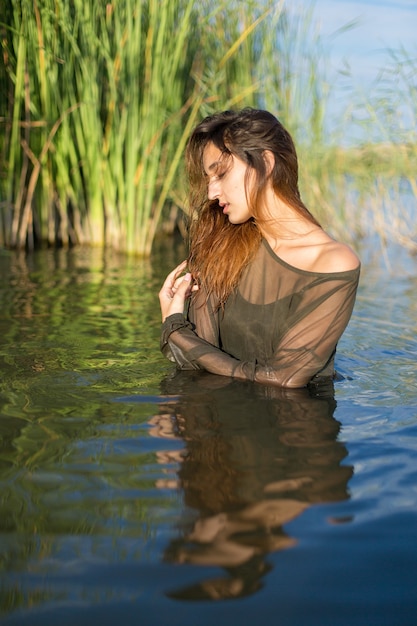 Chica mojada en el agua con cañas, retrato emocional de una chica en el agua