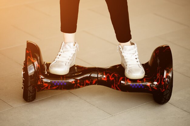 Chica monta en gyroscooter. Las piernas del niño en zapatillas de deporte en mini segway