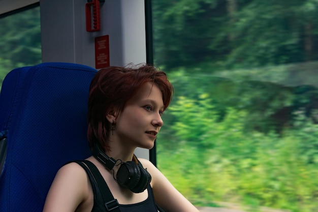 Chica monta un tren fuera de la ciudad y mira por la ventana un paisaje natural borroso en movimiento