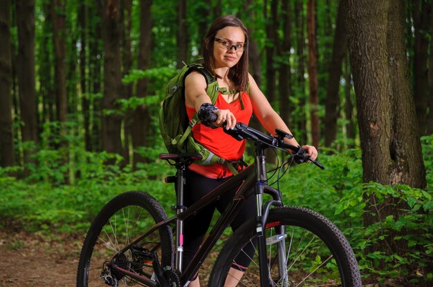 Chica montando una bicicleta en el bosque