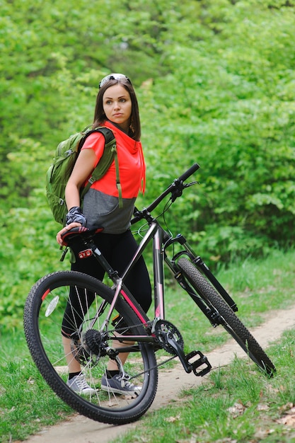 Chica montando una bicicleta en el bosque