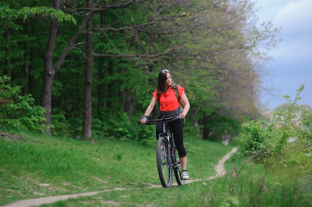 Chica montando una bicicleta en el bosque
