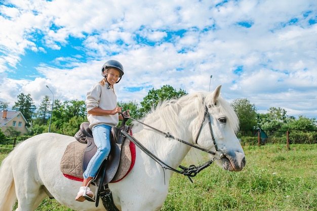 Chica montando un caballo blanco en la naturaleza