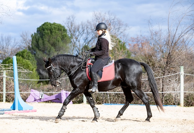 Chica montando está entrenando a su caballo negro