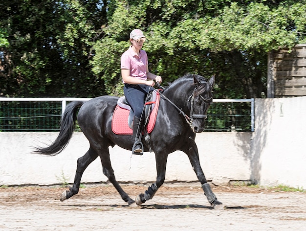 Chica montando está entrenando a su caballo negro