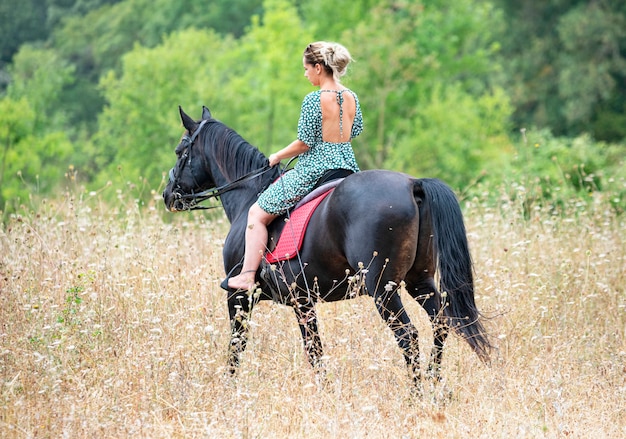 Chica de montar camina con su caballo negro