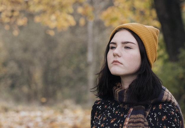 Chica morena adolescente triste en el parque de otoño