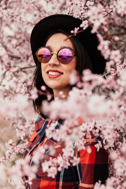 Chica morena atractiva cerca de un almendro