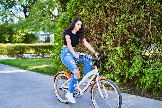 Chica morena en bicicleta en la ciudad