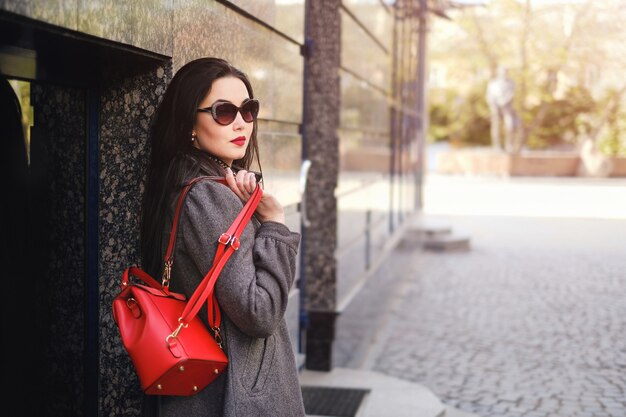 Chica morena caminando en la calle con mochila roja