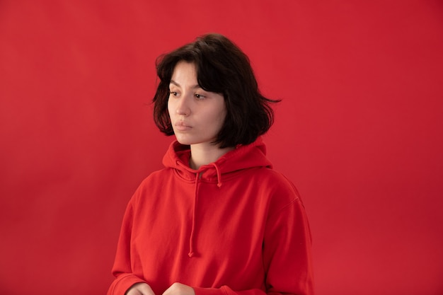 Foto chica morena cansada en sudadera con capucha roja posando