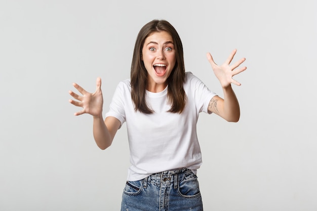 Chica morena emocionada sonriendo asombrada y levantando las manos para atrapar algo.