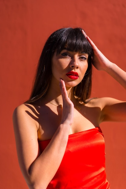 Chica morena de fondo rojo y vestido ajustado rojo Día de San Valentín